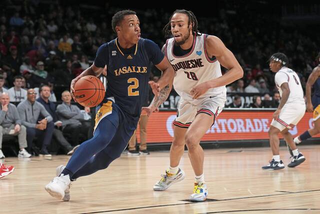 LaSalle’s Jhamir Brickus drives to the basket as Duquesne’s Joe Reece defends in the first half during a second-round game at the Atlantic 10 Tournament on Wednesday at Barclays Center in Brooklyn.