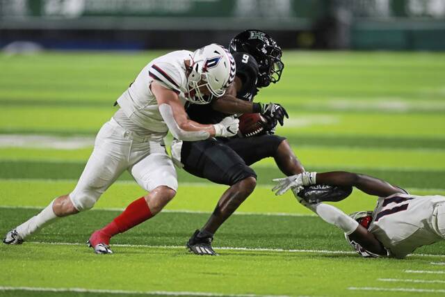 Duquesne linebacker Shane Stump, left, and defensive back Jaelen Carson (11) tackle Hawaii wide receiver Dior Scott (9) during the first half of an NCAA college football game Saturday, Sept. 17, 2022, in Honolulu.