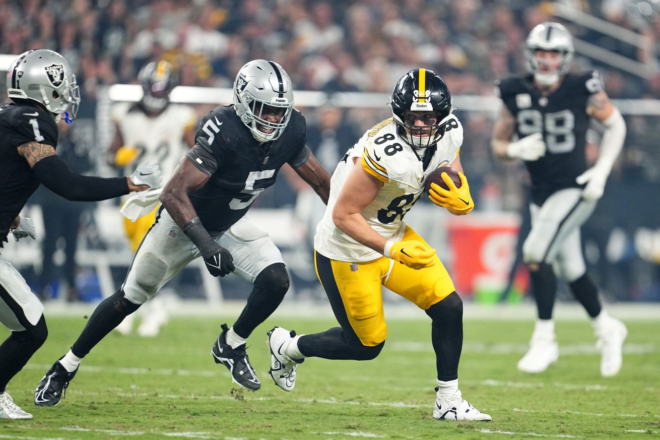 Pittsburgh Steelers tight end Pat Freiermuth moves downfield as multiple Las Vegas Raiders attempt to bring him down during a 2023 regular season contest.