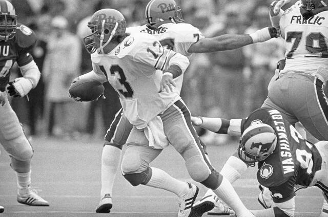 University of Pittsburgh quarterback Dan Marino (13) makes his move to elude the tackle attempt by Southern Methodist University defensive end Russell Washington, right, during first quarter action in the Cotton Bowl, Jan. 1, 1983 in Dallas. Marino gained two yards on the scramble.