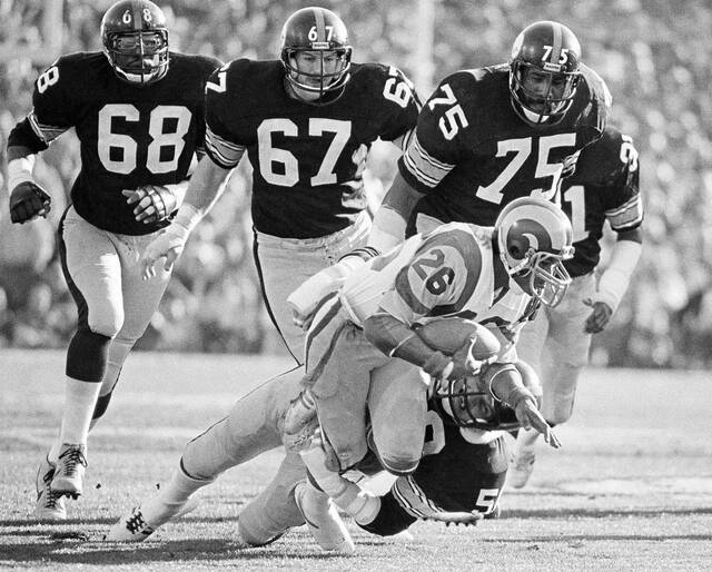 Los Angeles Rams running back Wendell Tyler (26) is thrown for 4-yard loss by Pittsburgh Steelers linebacker Jack Lambert (58) as Steelers L.C. Greenwood (68), Gary Dunn (67) and Joe Greene (75) look on during first quarter of Super Bowl XIV.