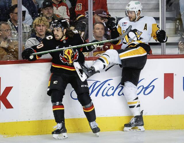 Pittsburgh Penguins’ Kris Letang, right, is checked by Calgary Flames’ Ryan Lomberg during the second period of an NHL hockey game on Tuesday, Oct. 22, 2024 in Calgary, Alberta.