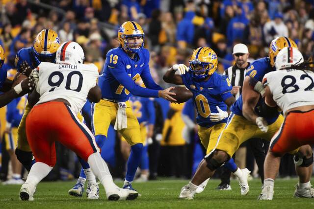 Pitt’s quarterback Nate Yarnell hands off to Desmond Reid after starting quarterback Eli Reid was taken out from play with a head injury during their game against Virginia on Saturday, Nov. 9, 2024 at Acrisure Stadium.