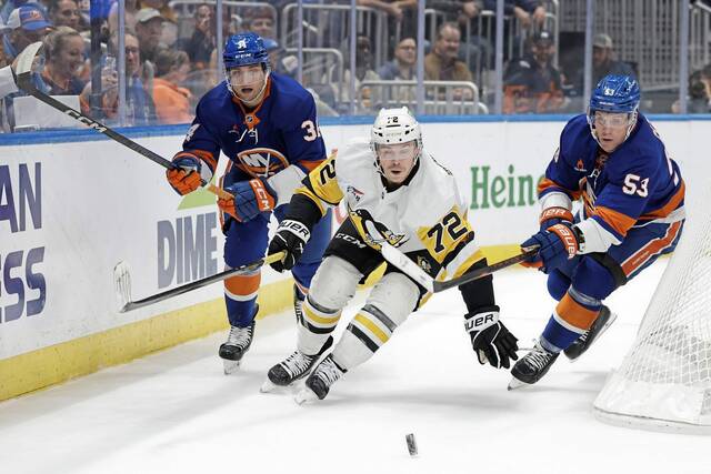 Pittsburgh Penguins left wing Anthony Beauvillier (72) battles for the puck with New York Islanders center Casey Cizikas (53) and Grant Hutton (34) in the first period of an NHL hockey game Tuesday, Nov. 5, 2024, in Elmont, N.Y.