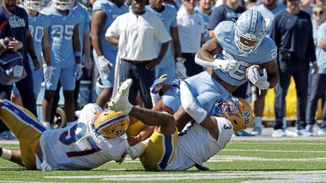 North Carolina running back Omarion Hampton (28) is tackled by Pittsburgh defensive lineman Isaiah Neal (97) and defensive back Donovan McMillon (3) during the first half of an NCAA college football game Saturday, Oct. 5, 2024, in Chapel Hill, N.C. (AP Photo/Chris Seward)