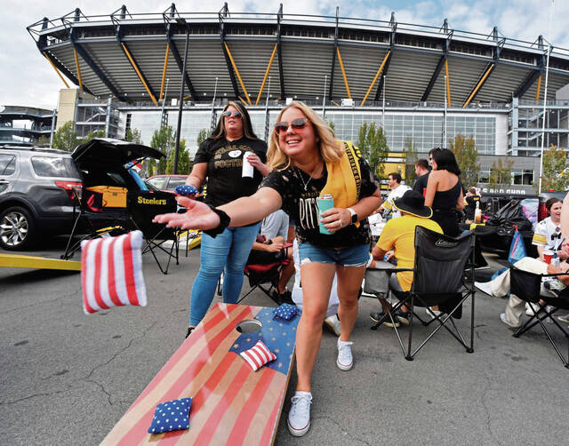 Steelers fan Kelly Ladisic of Plum plays corn hole while tailgating before the home opener agains the Patriots Sunday, Sept. 18, 2022 at Acrisure Stadium.