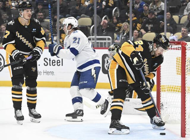 Tampa Bay Lightning forward Brayden Point celebrates a game-winning goal as Penguins forward Rickard Rakell (left) and defenseman Matt Grzelcyk skate away during a game at PPG Paints Arena on Tuesday. The Lightning won in overtime, 3-2.