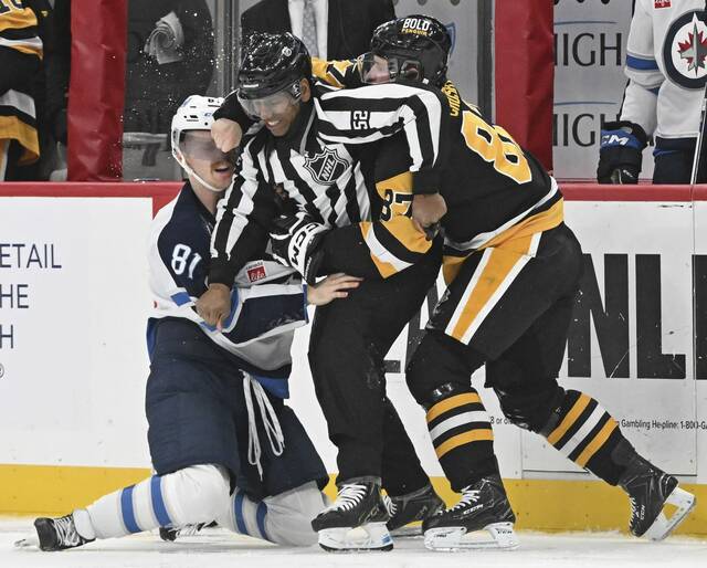 Linesman Shandor Alphonso tries to get between the Penguins’ Sidney Crosby and Jets’ Kyle Connor but Crosby gets a punch off in the third period Friday at PPG Paints Arena.