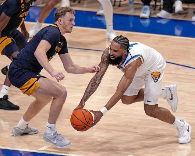 Pittsburgh’s Damian Dunn (1) is defended by West Virginia’s Tucker DeVries during the first half of an NCAA college basketball game Friday, Nov. 15, 2024, in Pittsburgh. (AP Photo/Gene J. Puskar)