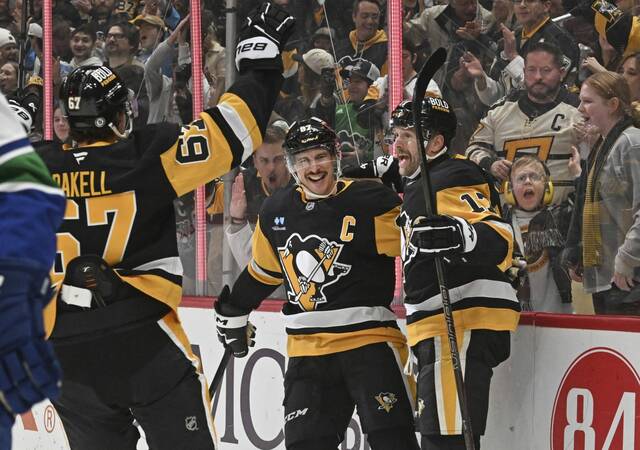 Penguins forwards Rickard Rakell (left) and Sidney Crosby (center) celebrate a goal with forward Bryan Rust during a 5-4 win against the Vancouver Canucks at PPG Paints Arena on Wednesday.