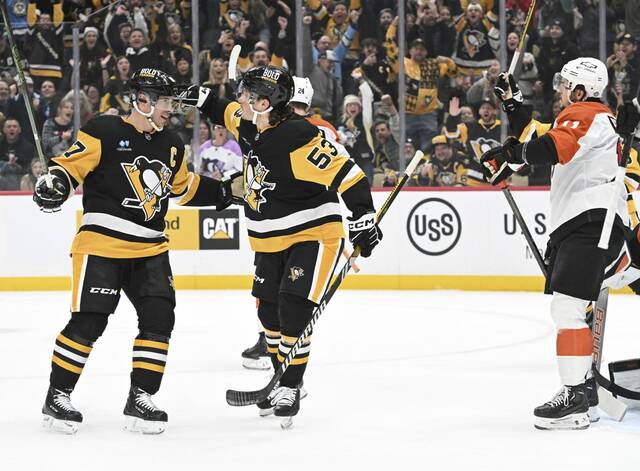 The Penguins’ Sidney Crosby (left) celebrates with Philip Tomasino after Tomasino’s goal against the Flyers in the first period Monday at PPG Paints Arena.