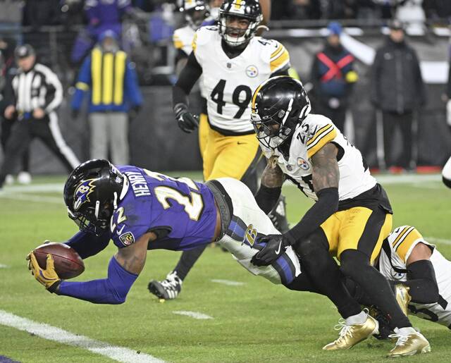 Ravens running back Derrick Henry stretches the ball across the goal line past the Steelers’ Minkah Fitzpatrick and DeShon Elliott in the second quarter Saturday.