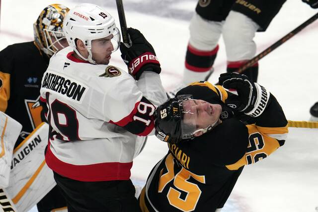 The Penguins’ Noel Acciari recoils after get a high stick in the chin from the Senators’ Drake Batherson during the first period Saturday.