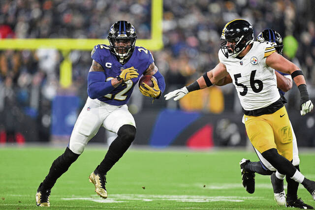 Baltimore Ravens running back Derrick Henry (22) runs the ball as Pittsburgh Steelers linebacker Alex Highsmith (56) pursues during the first half of an NFL wild card playoff football game, Saturday, Jan. 11, 2025, in Baltimore. (AP Photo/Terrance Williams)