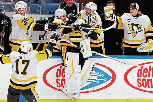 Penguins goaltender Alex Nedeljkovic, center, celebrates with teammates after scoring during the third period against the Sabres on Friday.