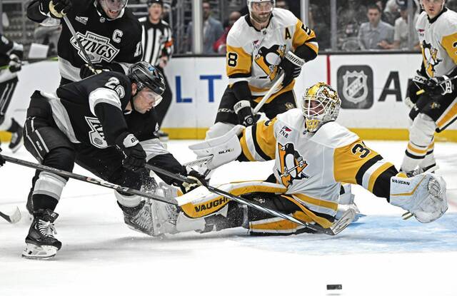 Los Angeles Kings left wing Kevin Fiala (22) reaches for the puck as Penguins goaltender Alex Nedeljkovic reaches to make a save during the second period Monday in Los Angeles.