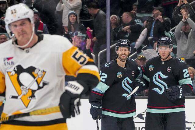 Kraken defenseman Vince Dunn, right, celebrates his goal with right wing Oliver Bjorkstrand as Penguins center Noel Acciari reacts during the second period Saturday.