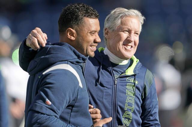 From Oct. 31, 2021: Seahawks head coach Pete Carroll (right) throws his arm around quarterback Russell Wilson as they walk on the field ahead of a game against the Jacksonville Jaguars in Seattle.