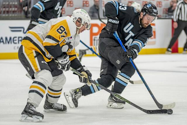 Penguins center Sidney Crosby and Utah Hockey Club forward Michael Carcone go for the puck during the second period Wednesday.